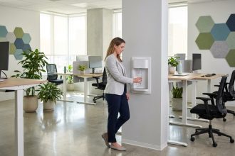 Distributeur d'eau compact intégré contre une cloison en open space moderne avec une employée remplissant sa gourde